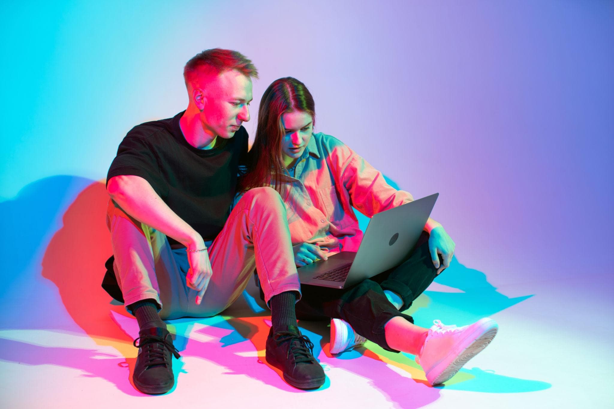 Dois sócios sentados no chão olhando os números no notebook